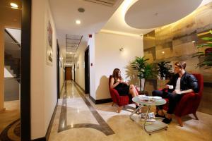zwei Personen, die in einer Lobby auf Stühlen sitzen in der Unterkunft Buca Residence Hotel in Izmir
