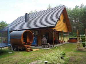 a large wooden house with a large wooden barrel at Bochenówka in Rogowo
