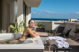 a woman sitting in a bath tub on a balcony at Metropole Urban Hotel in Heraklio