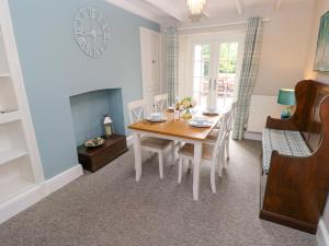 a dining room with a table and a fireplace at Orielton Cottage in Dinas