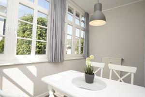 a white dining room with a table and two windows at Wintergarten, gratis Nutzung vom AHOI Erlebnisbad in Sellin - Villa Maria FeWo Marlene 34 in Göhren