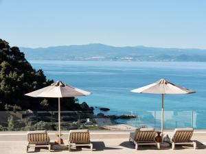 a group of chairs and umbrellas next to the ocean at Cora Hotel & Spa in Afitos