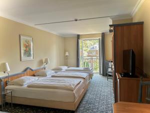 a hotel room with three beds and a flat screen tv at Country Hotel Timmendorfer Strand in Timmendorfer Strand