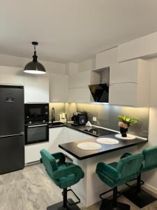 a kitchen with a counter and two green chairs at Apartament Prima Arena in Oradea