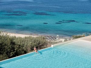 a woman in a swimming pool next to the ocean at Cora Hotel & Spa in Afitos