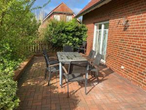 un tavolo e sedie seduti su un patio in mattoni di Freistehendes Haus mit großem, eingezäunten Garten, Sauna, Kamin a Krummhörn