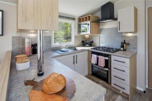 a kitchen with white cabinets and a wooden table at Castle Archdale Holiday Park in Enniskillen