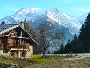 un edificio con un albero e montagne sullo sfondo di La ferme des ours - sur les pistes, vue Mont-Blanc a Saint-Gervais-les-Bains