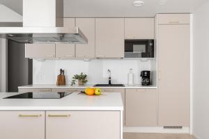 a white kitchen with white cabinets and fruit on the counter at Borg Katarina - Riverside View in Pori