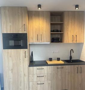 eine Küche mit Holzschränken und schwarzen Geräten in der Unterkunft Luxury Bungalow Sonnenland in Sonnenland