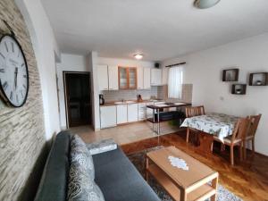 a living room with a couch and a clock on a wall at Apartmani Katarina&Ivan Krstinić in Rab
