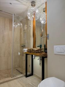 a bathroom with a shower with a table and chandeliers at The One Apartments in Siófok +27 photos