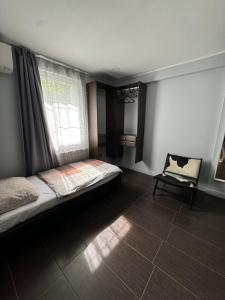 a bedroom with a bed and a window and a chair at The One Apartments in Siófok