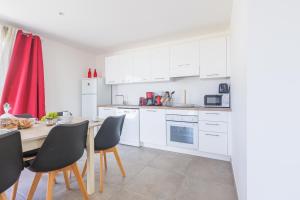 une cuisine avec des armoires blanches et une table et des chaises dans l'établissement Casa Umbria - Villa climatisée avec piscine, à Belgodère