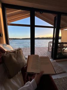 a person reading a book with a view of the water at Domy na wodzie Sztynort in Sztynort +8 photos
