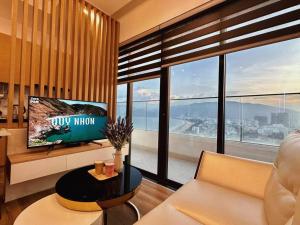 un salon avec une télévision et une grande fenêtre dans l'établissement BBnB Home - Mai's House, à Quy Nhơn