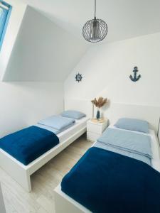 2 bedden in een witte kamer met blauwe lakens bij Apartament DWIE RYBKI in Pobierowo