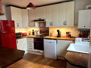 a kitchen with white cabinets and a red refrigerator at Hanushka in Hastings