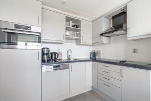 Una cocina blanca con gabinetes y electrodomésticos blancos. en Appartementencomplex Juliana 138, en De Koog