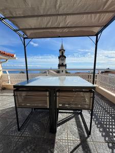 Una mesa en un patio con una torre de reloj al fondo. en Arco Apartment, en Arco da Calheta