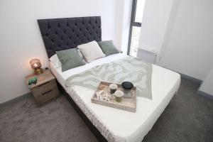 a bed with a tray with two cups on it at High Point 1 Bedroom Apartment in Bradford