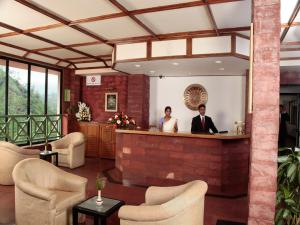 two people standing at a bar in a lobby at Abad Copper Castle Resort in Munnar