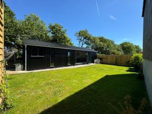 a backyard with a black house with a green yard at Lavish Dorset countryside retreat in Bradpole