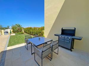 a grill and a table and chairs on a patio at Fantastic Villa, Private Pool, BBQ, AC and Wi-Fi in Quarteira