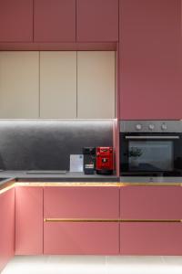 eine Küche mit rosa und weißen Schränken und einem roten Gerät in der Unterkunft The View - Ruby, Luxury, Central in Sarandë