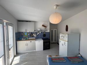 une cuisine avec des appareils électroménagers blancs et une lampe pendant dans l'établissement Luna Beach Apartment, à Novalja