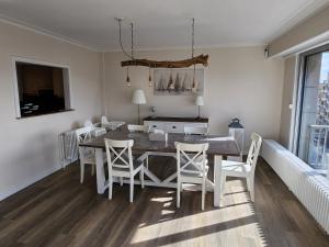 a dining room with a table and white chairs at Majestic in De Panne