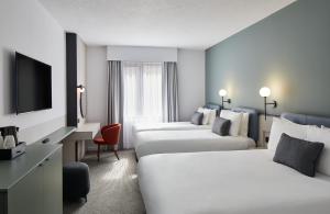 a hotel room with three beds and a television at Leonardo Hotel Dublin Parnell Street in Dublin