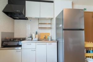 a kitchen with white cabinets and a stainless steel refrigerator at utazu stop in Utazu