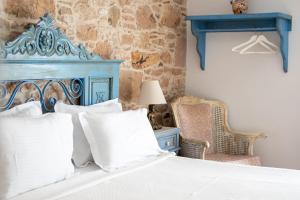 a bedroom with a bed with a blue headboard and a chair at cunda mor limon otel in Ayvalık