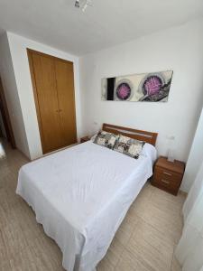 ein Schlafzimmer mit einem weißen Bett und einer Holztür in der Unterkunft Apartamentos D&D VISTAMAR 1 línea in Castellón de la Plana