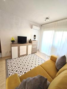 ein Wohnzimmer mit Sofa und Fernseher in der Unterkunft Apartamentos D&D VISTAMAR 1 línea in Castellón de la Plana