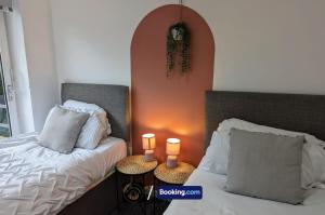 a bedroom with two beds and two lamps on tables at Cosy 3-Bed Home, Free Parking & WiFi in Bolton