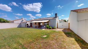 a backyard with a white fence and a house at Fleur de Sel in Saint-Gilles-Croix-de-Vie