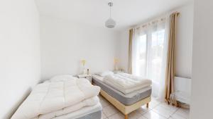 two beds in a white room with a window at Fleur de Sel in Saint-Gilles-Croix-de-Vie