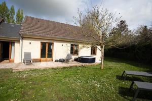ein kleines weißes Haus mit einer Terrasse und einem Baum in der Unterkunft La Longère avec Piscine in Saint-Martin-le-Gaillard