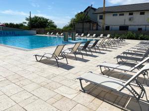 a row of lounge chairs and a swimming pool at BC Aprilia in Corbu