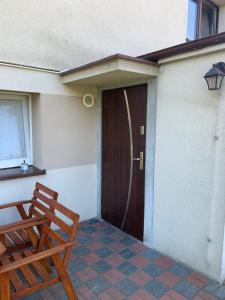 a door to a house with two wooden chairs at Apartament ~ Nad Zatoką in Jastarnia