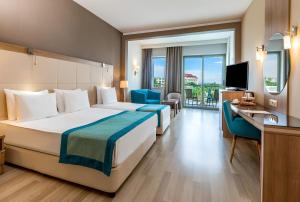 a hotel room with a bed and a desk and a television at Kaya Side in Side