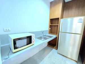 Una pequeña cocina con microondas y nevera. en Family room, en Ban Phayun