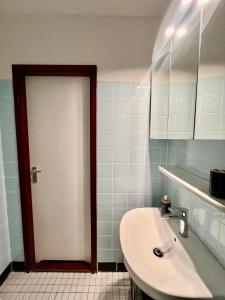 a bathroom with a sink and a white door at Panoramic View Harz in Altenau +1 photo