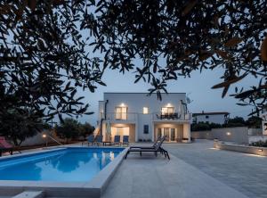a villa with a swimming pool in front of a house at Holiday Home Milutin 1 in Vrsi