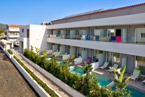an apartment building with a swimming pool and chairs at White Olive Premium Laganas in Laganas