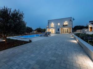a house with a patio and a swimming pool at Holiday Home Milutin 1 in Vrsi