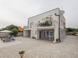 a large white house with a balcony and a patio at Holiday Home Milutin 1 in Vrsi