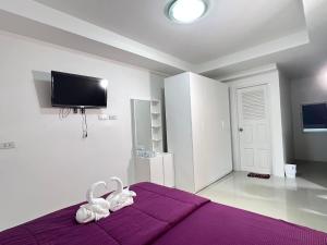 a bedroom with a purple bed with a tv on the wall at Suksiri Banlaem in Ban Laem